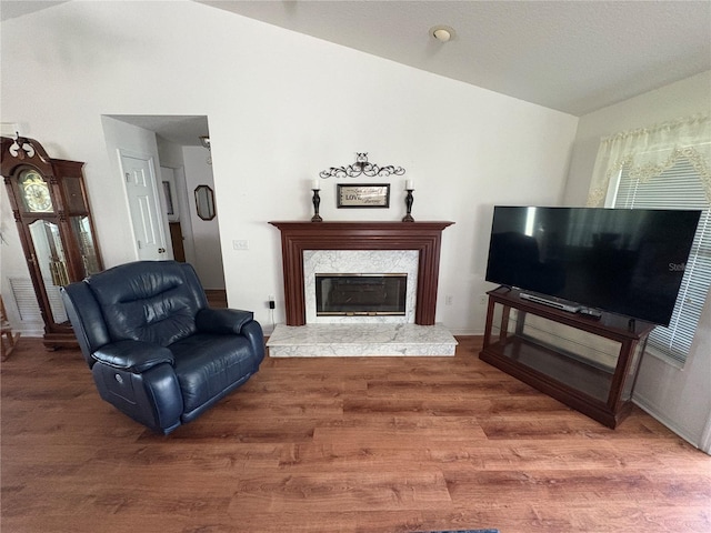 living room featuring lofted ceiling, a premium fireplace, and wood finished floors