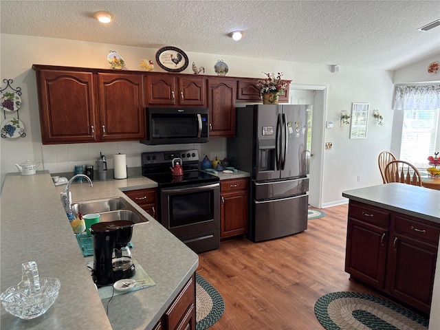 kitchen with a textured ceiling, appliances with stainless steel finishes, light countertops, and a sink