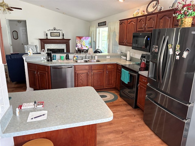 kitchen with a sink, light wood-style floors, stainless steel appliances, light countertops, and a peninsula