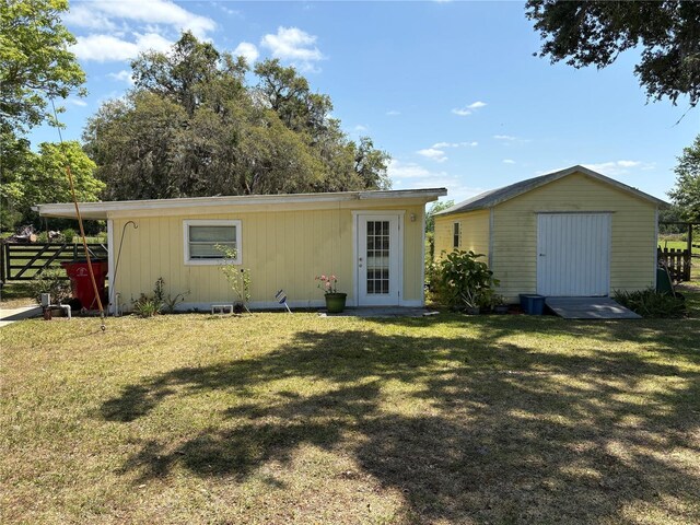 ranch-style house with fence, an outdoor structure, a front yard, and a storage shed