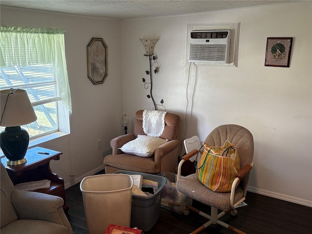 sitting room featuring a textured ceiling, baseboards, ornamental molding, an AC wall unit, and wood finished floors