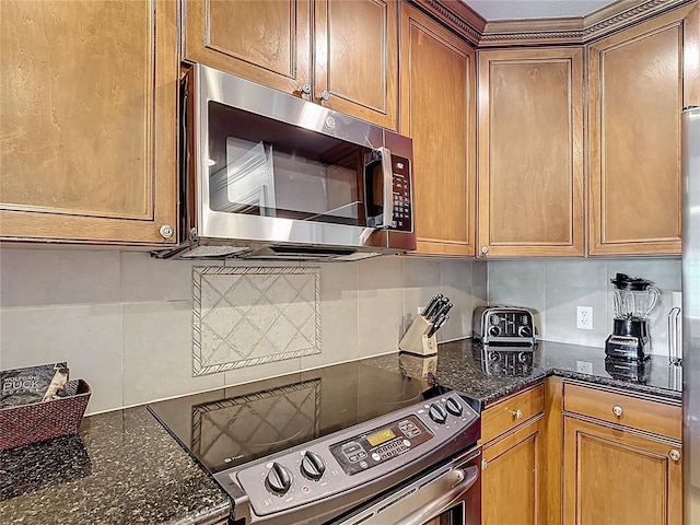 1356 Centre Court Ridge Dr Unit 103, Reunion, FL 34747 - kitchen featuring tasteful backsplash, brown cabinetry, stainless steel appliances, and dark stone countertops