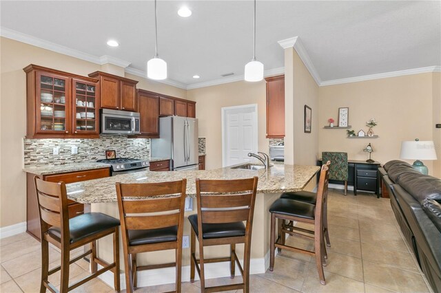 kitchen with tasteful backsplash, a sink, glass insert cabinets, stainless steel appliances, and a kitchen bar
