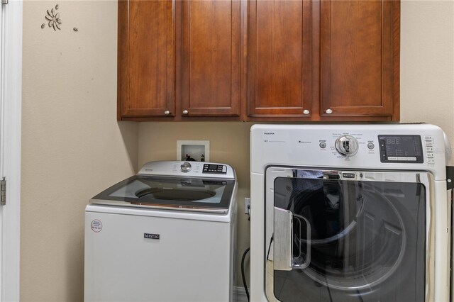 clothes washing area featuring washer and dryer and cabinet space