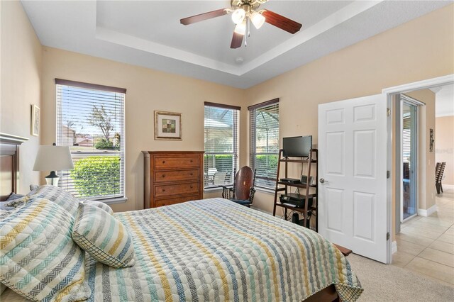 bedroom featuring light tile patterned flooring, baseboards, light colored carpet, ceiling fan, and a raised ceiling
