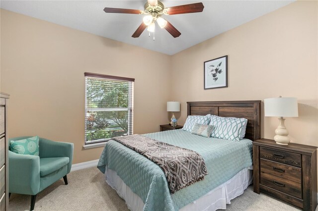 bedroom featuring light carpet, a ceiling fan, and baseboards