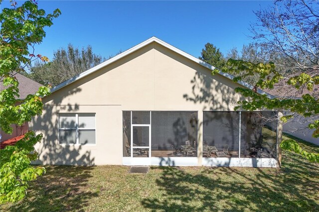 rear view of house featuring a sunroom and a yard