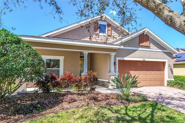 craftsman house featuring covered porch, an attached garage, stucco siding, and driveway