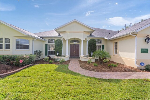 1721 Sunset Ridge Dr, The Villages, FL 32162 - view of front facade with a front yard, stucco siding, and roof with shingles