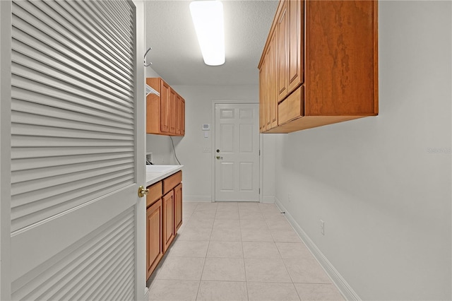 1721 Sunset Ridge Dr, The Villages, FL 32162 - laundry area featuring light tile patterned floors, cabinet space, baseboards, and washer hookup