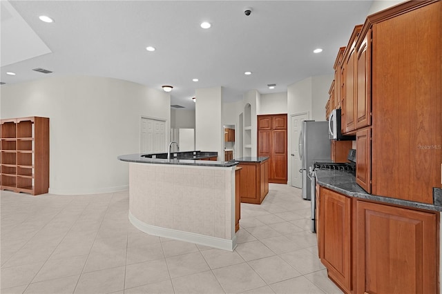 1721 Sunset Ridge Dr, The Villages, FL 32162 - kitchen with appliances with stainless steel finishes, brown cabinets, a center island, recessed lighting, and light tile patterned floors
