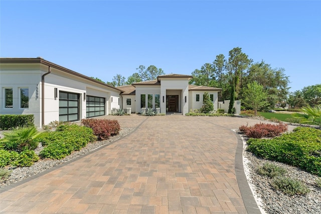 prairie-style home with a garage, stucco siding, and decorative driveway
