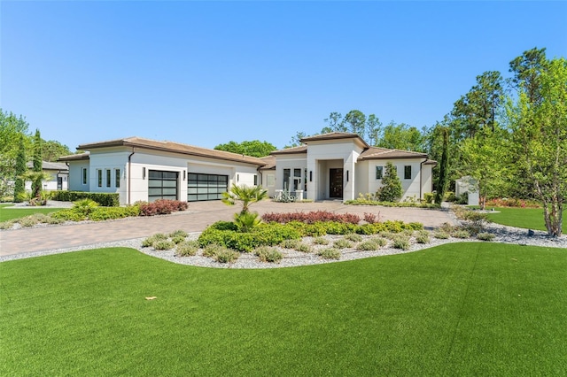 view of front of house with a garage, a front lawn, decorative driveway, and stucco siding