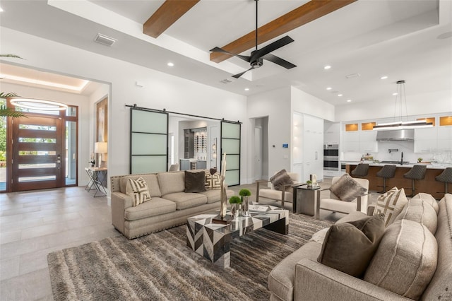 living room with beamed ceiling, recessed lighting, visible vents, and a barn door
