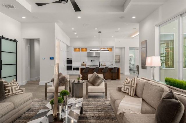 living area featuring recessed lighting, ceiling fan, a barn door, and baseboards