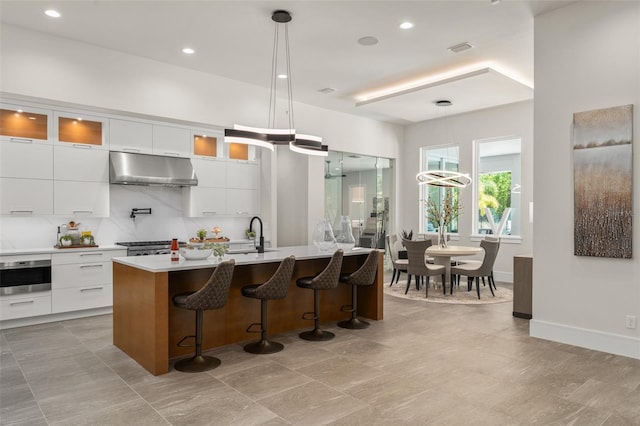 kitchen with a sink, modern cabinets, white cabinets, and under cabinet range hood
