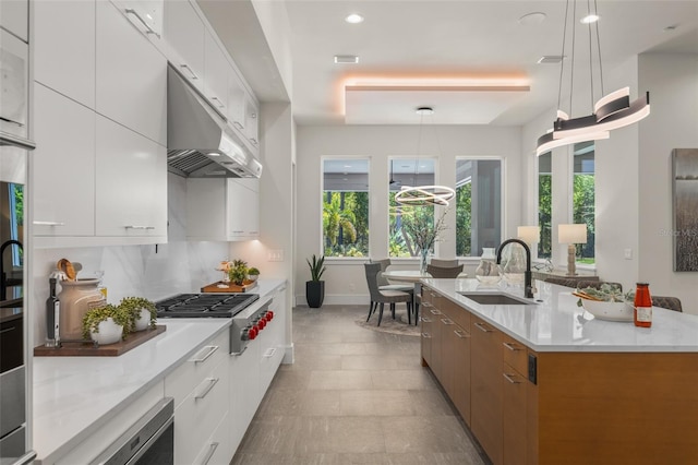 kitchen featuring stainless steel gas cooktop, modern cabinets, under cabinet range hood, and a sink