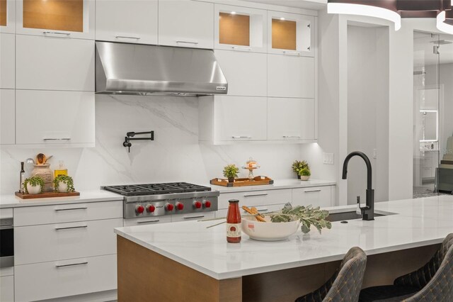 kitchen featuring modern cabinets, stainless steel gas stovetop, under cabinet range hood, and white cabinetry