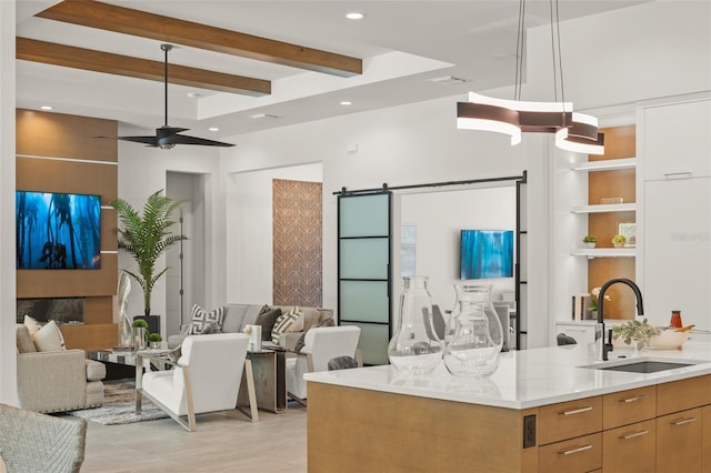 interior space featuring beamed ceiling, modern cabinets, a sink, light countertops, and open floor plan