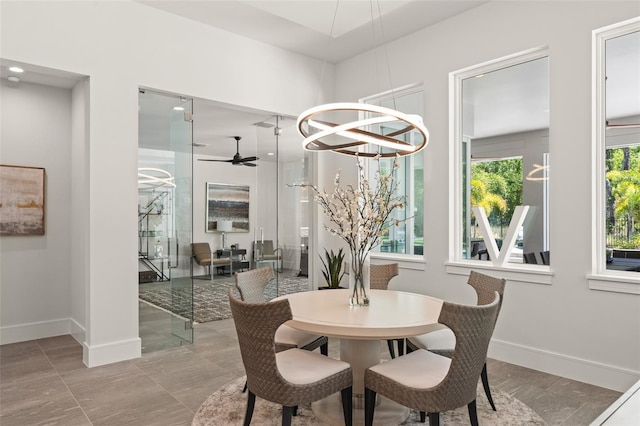 dining area featuring baseboards and ceiling fan with notable chandelier