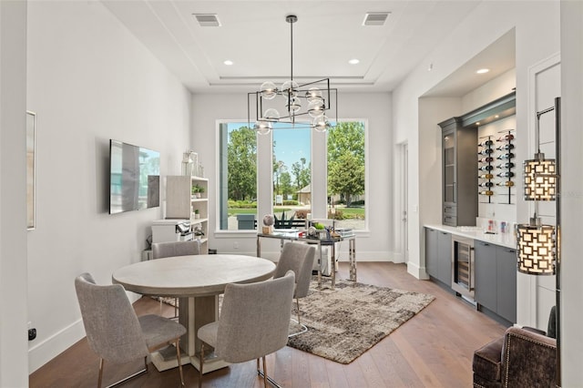 dining space with baseboards, visible vents, light wood-style flooring, and wine cooler
