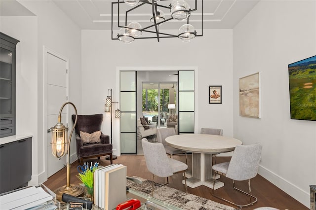 dining space with an inviting chandelier, baseboards, and dark wood finished floors