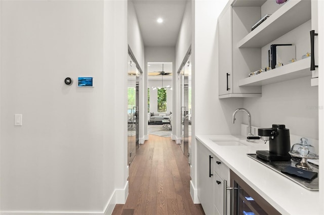 bar with recessed lighting, a sink, a ceiling fan, baseboards, and wood finished floors