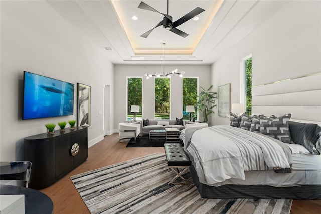 bedroom featuring a raised ceiling, wood finished floors, and multiple windows