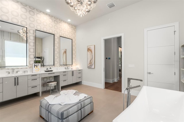 full bathroom featuring a freestanding bath, double vanity, a sink, visible vents, and a notable chandelier