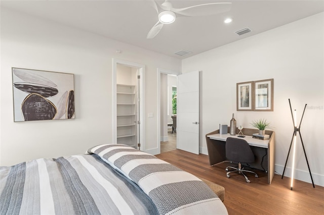 bedroom featuring wood finished floors, visible vents, a ceiling fan, and baseboards