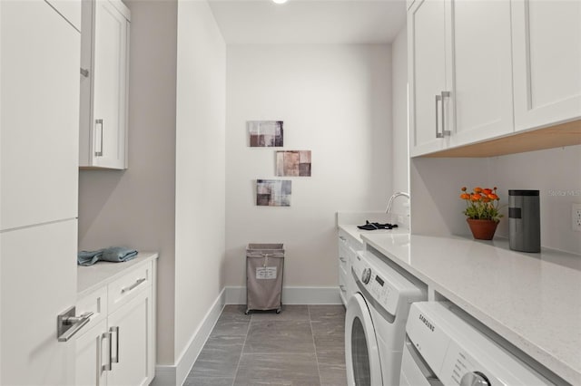 washroom with cabinet space, baseboards, and washer and clothes dryer