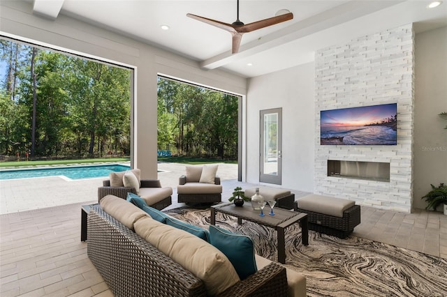 living area featuring beam ceiling, a ceiling fan, an outdoor stone fireplace, and recessed lighting