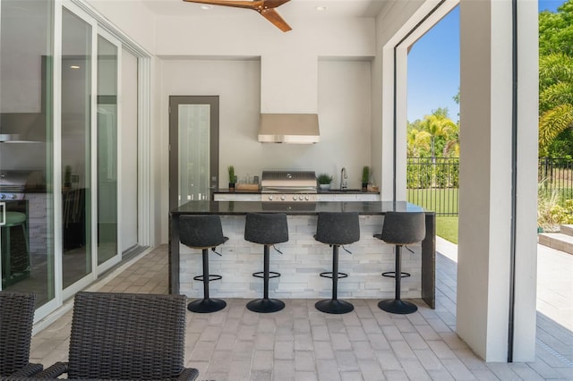 kitchen featuring a breakfast bar, recessed lighting, dark countertops, and a sink