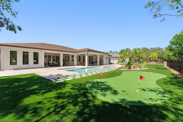 rear view of property featuring stucco siding, a yard, fence, a fenced in pool, and a patio