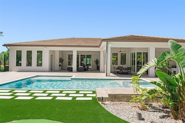 rear view of property featuring a fenced in pool, a patio, ceiling fan, and stucco siding