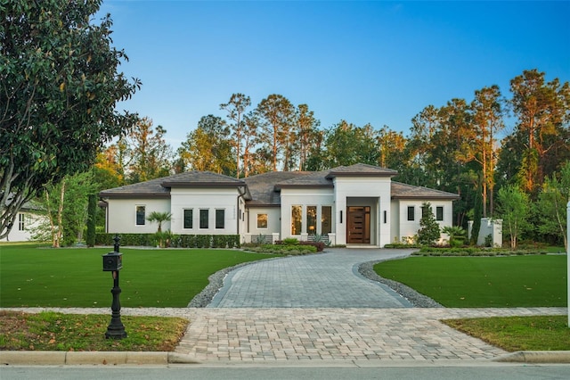 prairie-style house featuring curved driveway, stucco siding, and a front yard