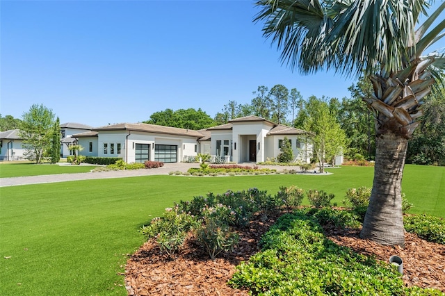 view of front of home featuring driveway, stucco siding, a front lawn, and a garage