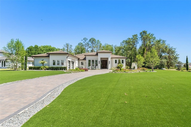 view of front of house featuring stucco siding, driveway, and a front lawn