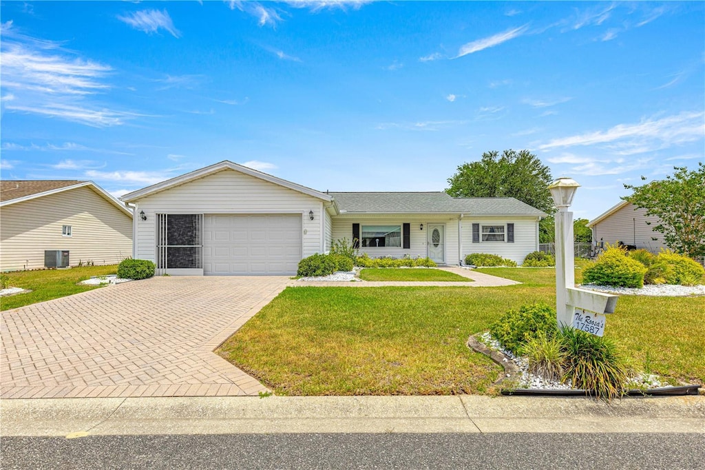 17587 SE 95th Cir, Summerfield, FL 34491 - ranch-style home featuring decorative driveway, central AC unit, a front yard, and a garage