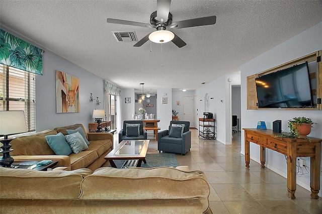 living room with a textured ceiling, visible vents, ceiling fan, and light tile patterned floors