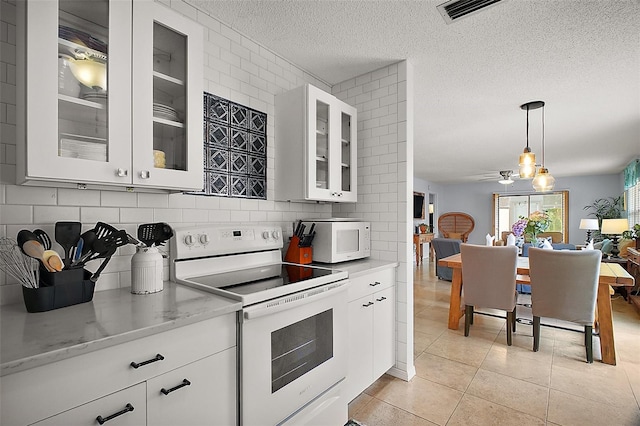 kitchen featuring light tile patterned flooring, tasteful backsplash, visible vents, white appliances, and a textured ceiling