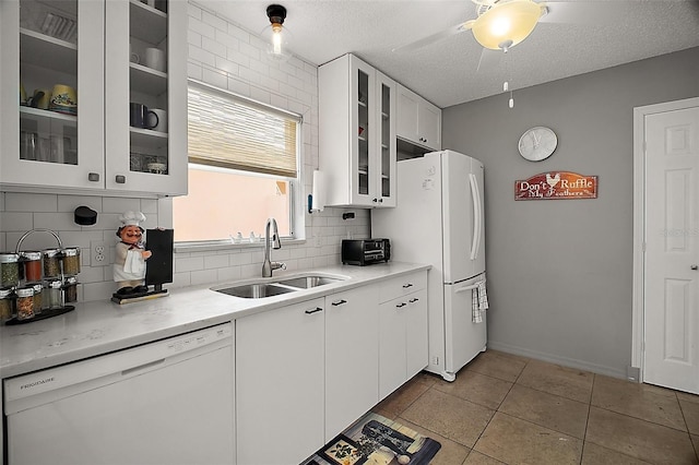kitchen featuring white appliances, glass insert cabinets, decorative backsplash, white cabinets, and a sink
