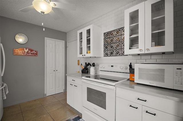 kitchen with a textured ceiling, white appliances, light countertops, and backsplash