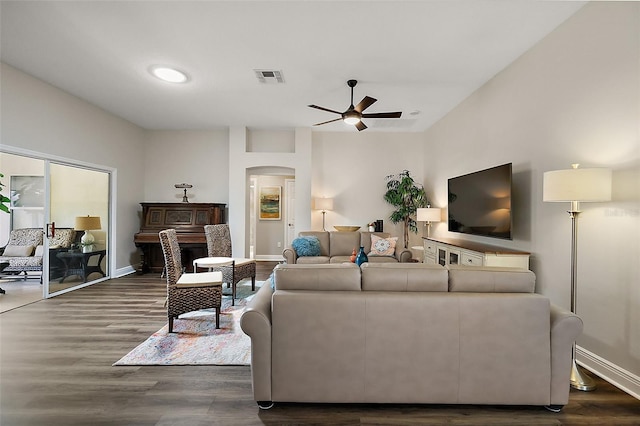 living room with ceiling fan, visible vents, dark wood finished floors, and arched walkways