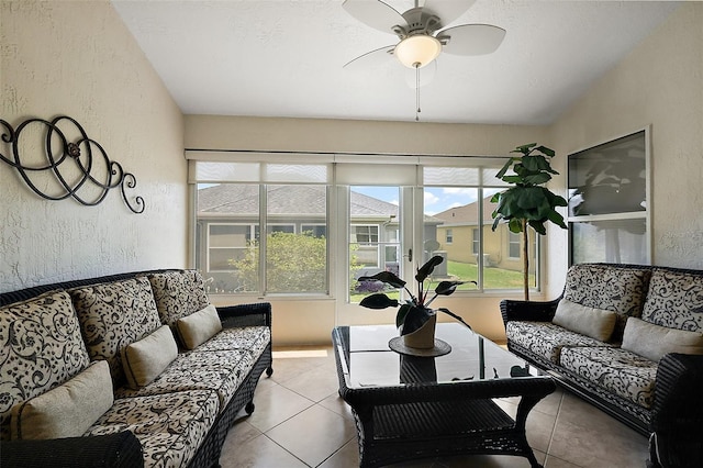 living room featuring ceiling fan, tile patterned flooring, a textured wall, and a sunroom