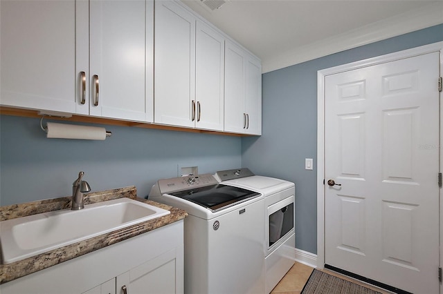 laundry room featuring a sink, baseboards, light tile patterned flooring, washer and clothes dryer, and cabinet space