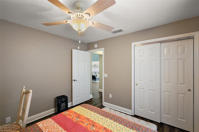 bedroom with visible vents, a closet, baseboards, dark wood-type flooring, and a ceiling fan