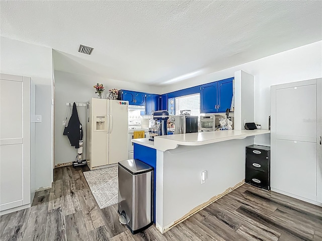 1001 N Lakeshore Blvd, Howey In The Hills, FL 34737 - kitchen with white appliances, visible vents, blue cabinets, a peninsula, and light countertops
