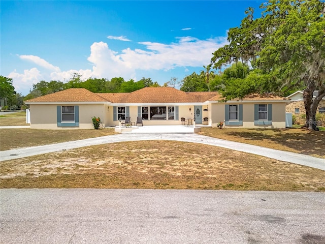 1001 N Lakeshore Blvd, Howey In The Hills, FL 34737 - ranch-style home featuring a front lawn, a porch, stucco siding, and curved driveway