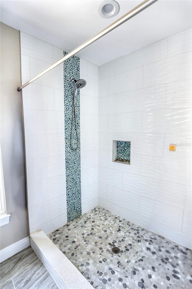bathroom featuring a tile shower and baseboards